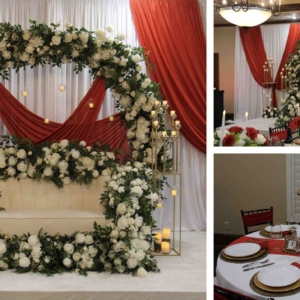 A beautiful floral arch adorned with white roses and greenery, set against a red drape backdrop on stage, with matching gold candelabras adding elegance.
